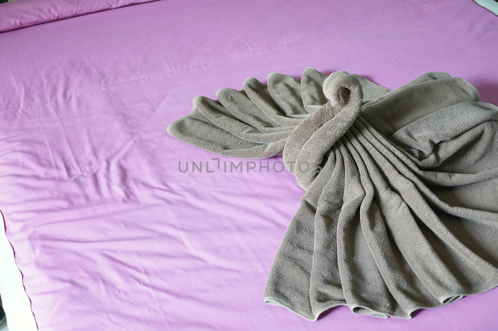 Brown towel plait as swan on pink bed by eaglesky