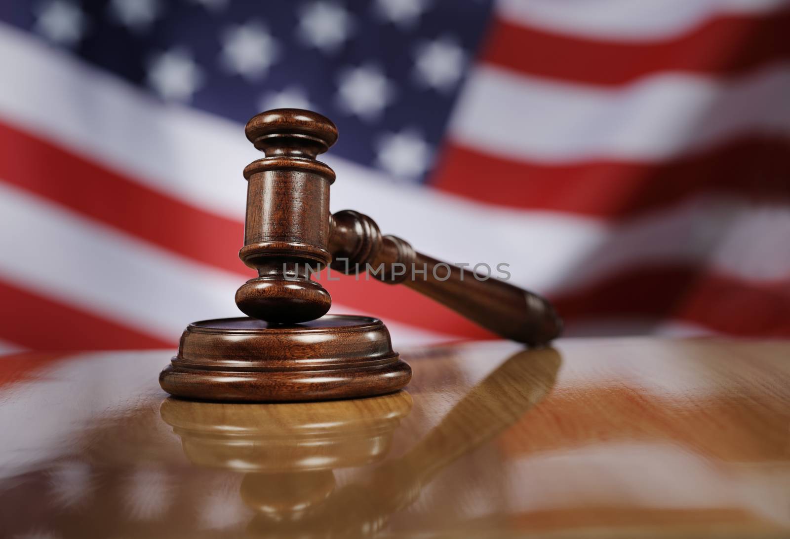 Mahogany wooden gavel on glossy wooden table, USA flag in the background.