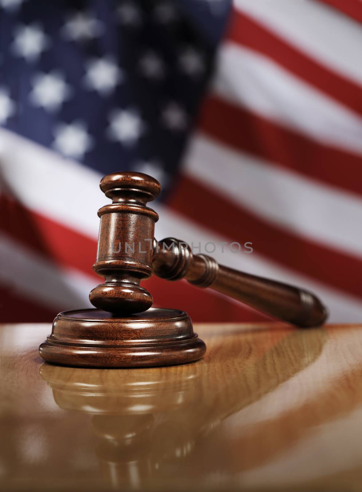 Wooden gavel on glossy table, The flag of USA in the background.