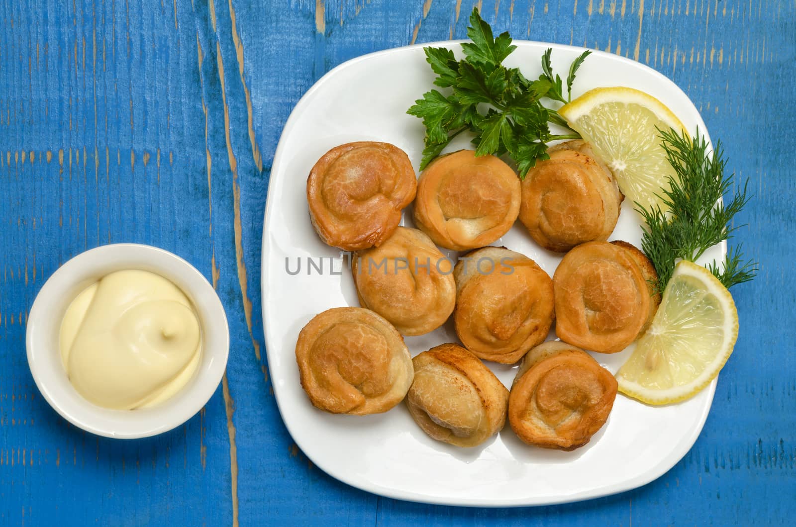Fried dumplings on the plate with mayonnaise, herbs and lemon. by Gaina