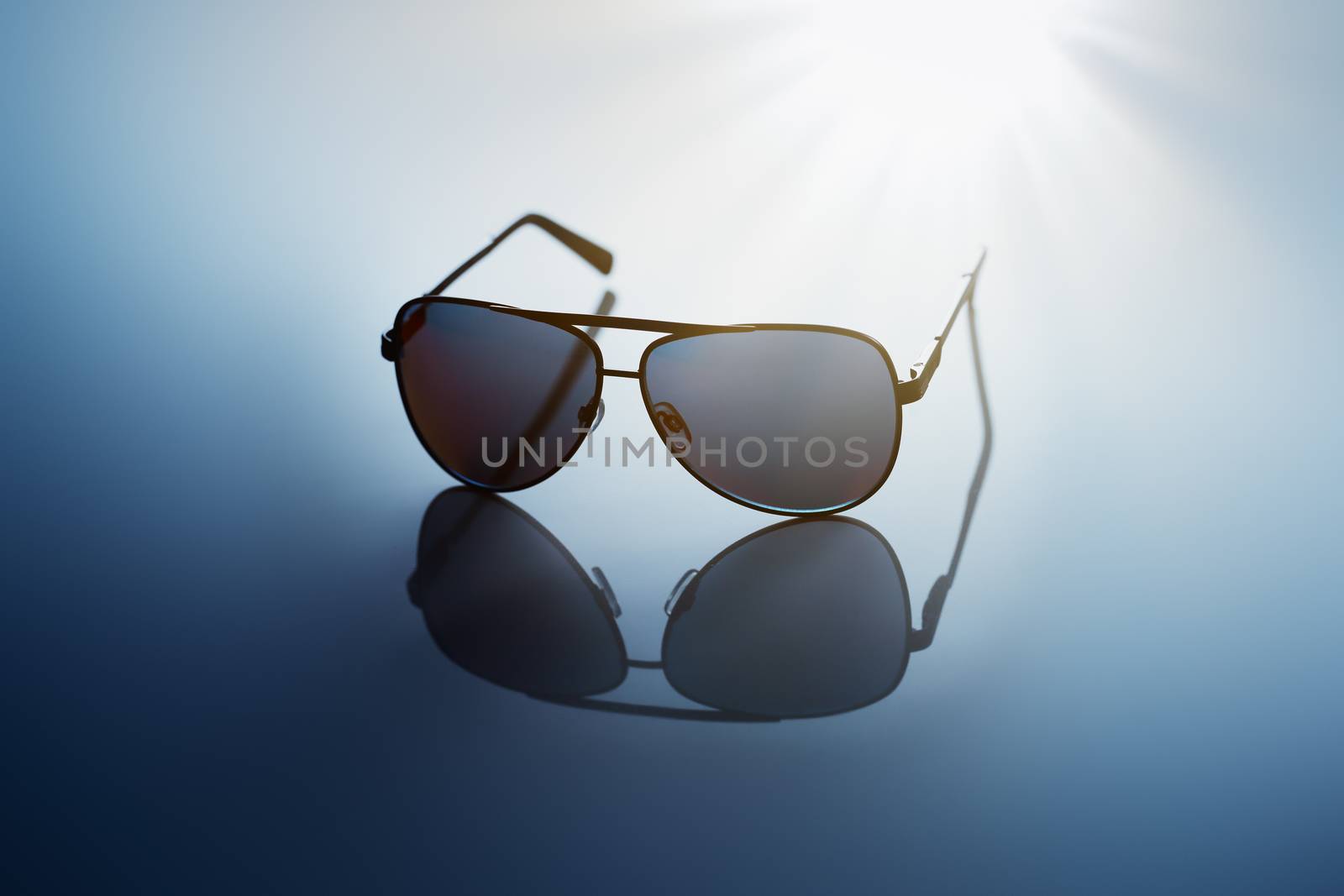 Sunglasses on blue reflective background.
