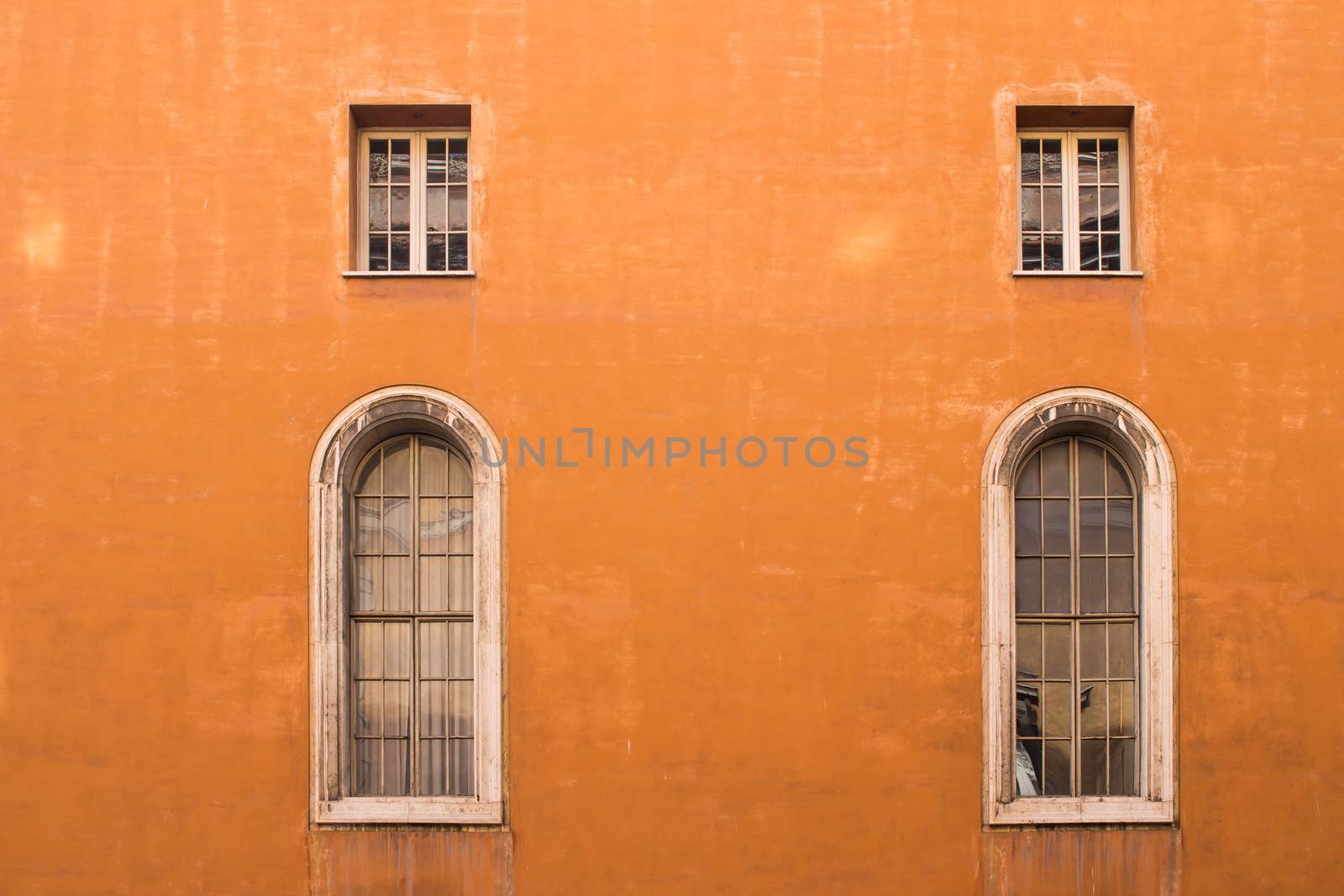 Typical orange color of the facade of a house in Rome. Big decorative windows and small traditional. Rome, Italy.