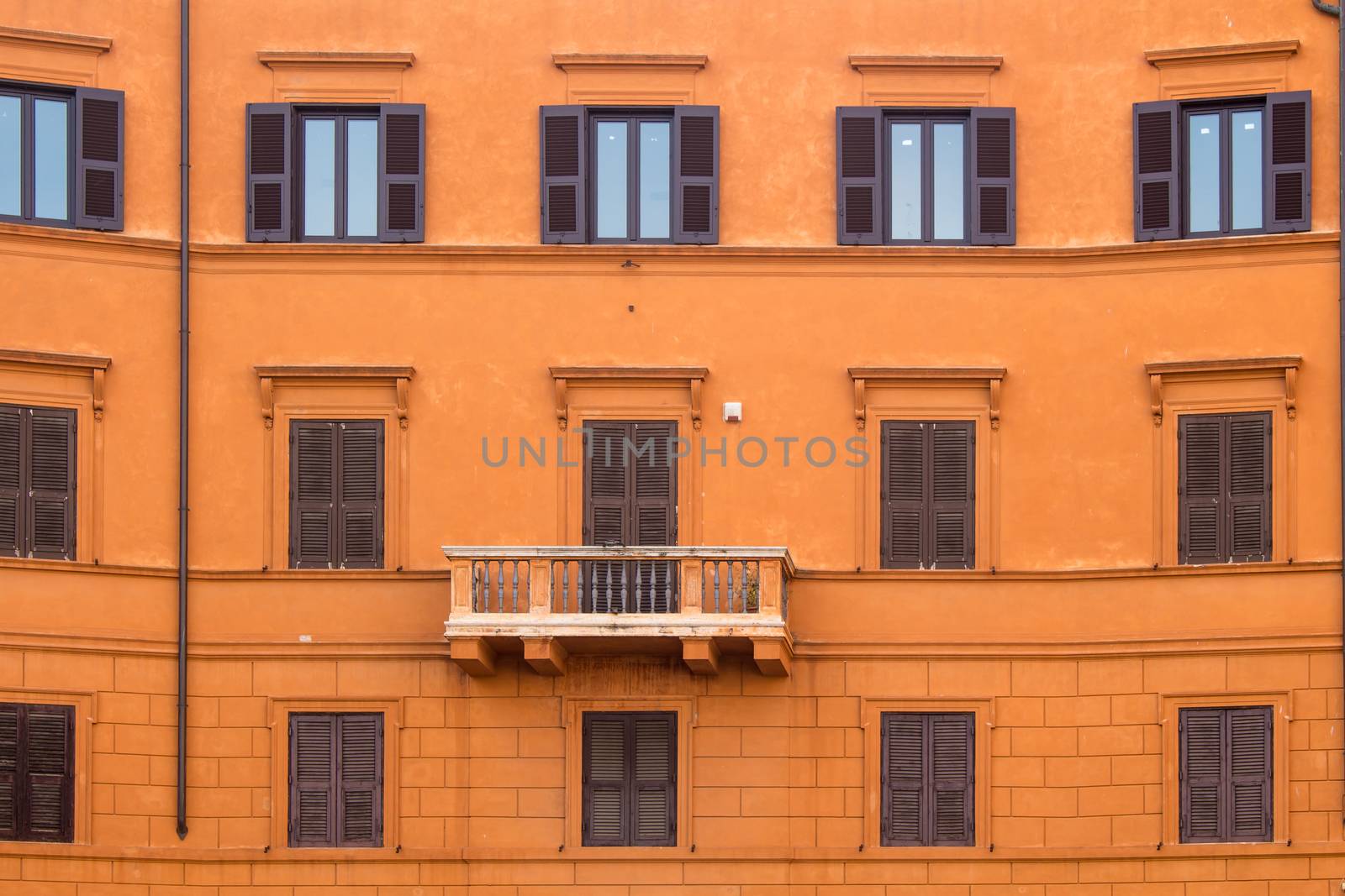 Typical orange color of the facade of a house in Rome. Windows reflecting the sky. Rome, Italy.