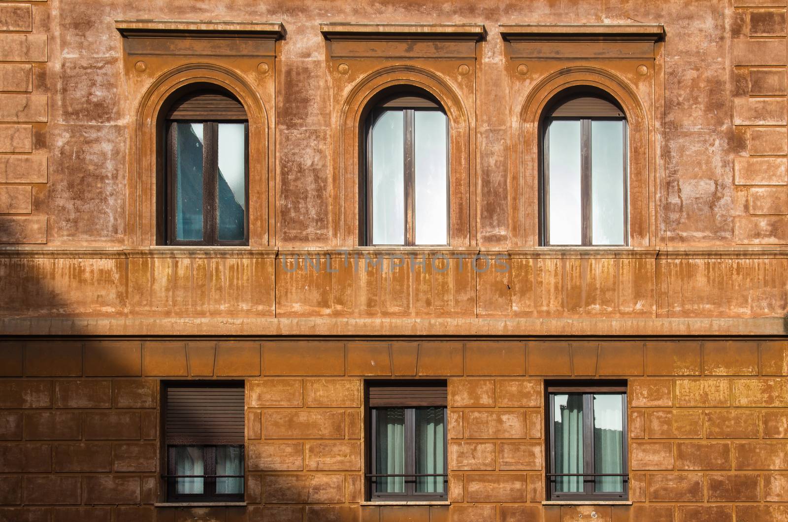 Typical orange color of the facade of a house in Rome. Windows reflecting the sky. Rome, Italy.