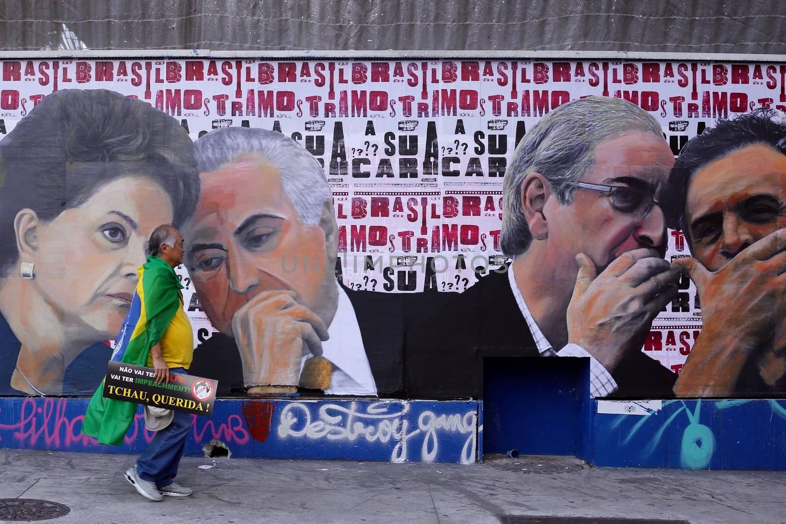 BRAZIl, Sao Paulo: A man holding a placard walks along a painted wall as thousands of activists supporting the impeachment of President Dilma Rousseff take part in a protest in Sao Paulo, on April 17, 2016. Brazilian lawmakers on Sunday reached the two thirds majority necessary to authorize impeachment proceedings against President Dilma Rousseff. The lower house vote sends Rousseff's case to the Senate, which can vote to open a trial. A two thirds majority in the upper house would eject her from office. Rousseff, whose approval rating has plunged to a dismal 10 percent, faces charges of embellishing public accounts to mask the budget deficit during her 2014 reelection.