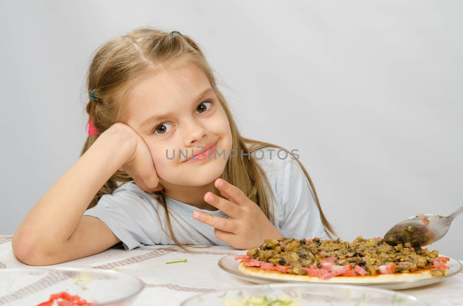 Little six year old girl sitting at the table waiting for about preparing pizza