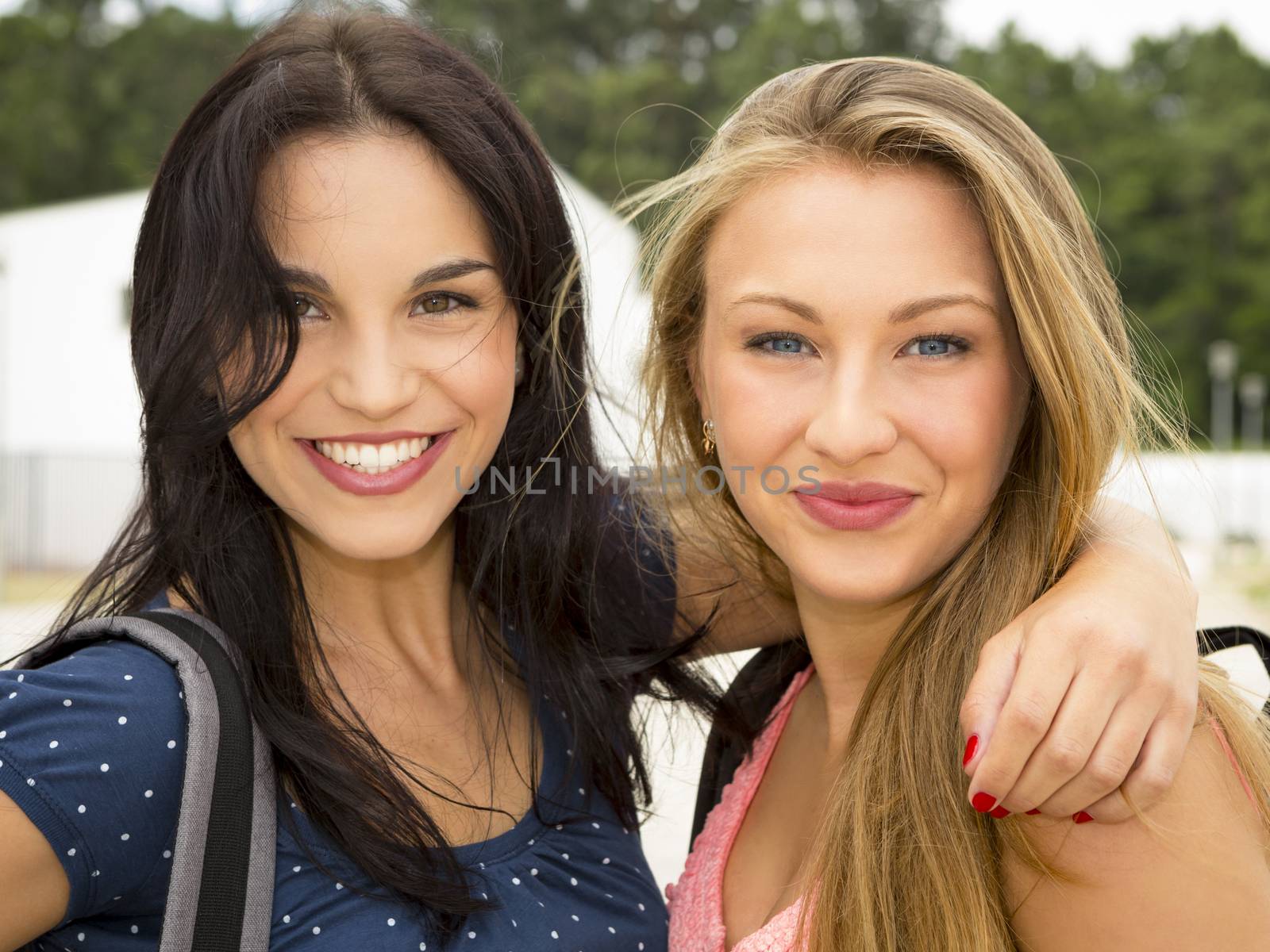 Two beautiful and happy teenage students smiling 