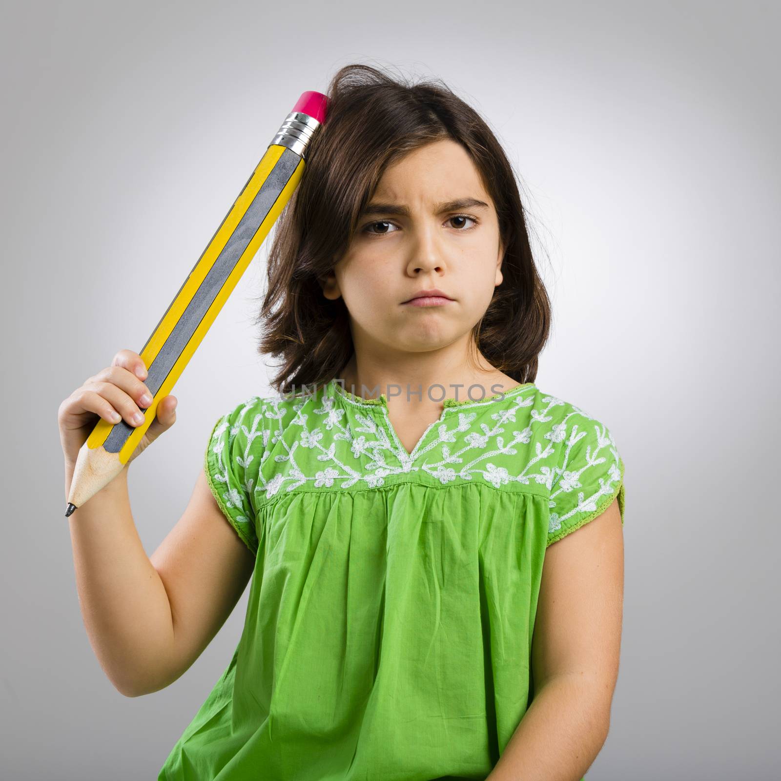 Studio portrait of a little girl thinking and scratching her head with a big pencil