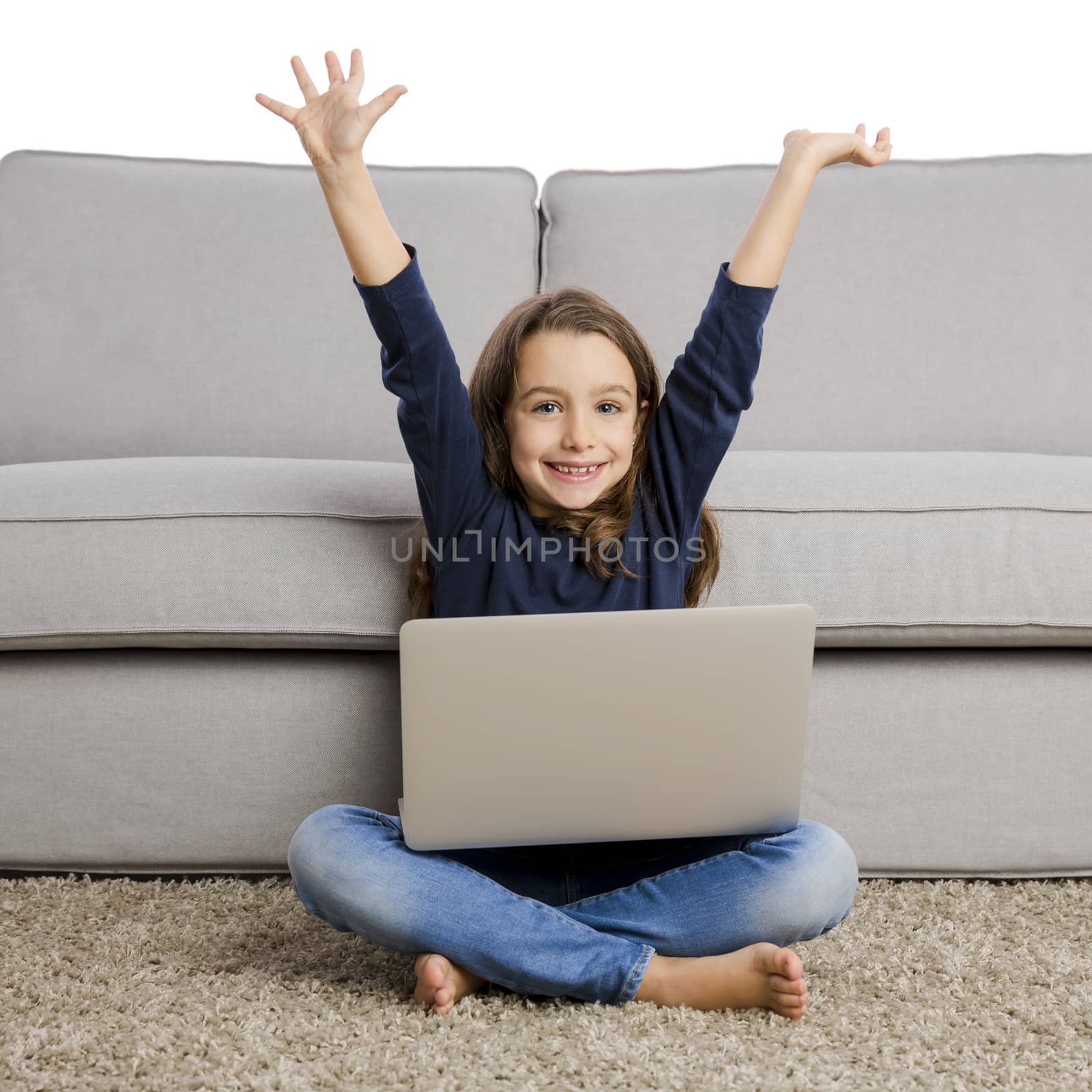 Happy little girl with arms open and working a laptop