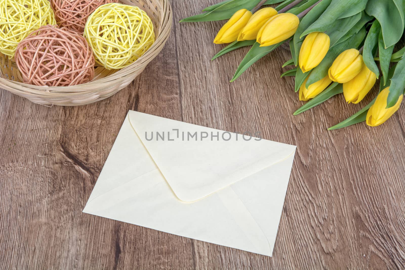 Envelope and yellow tulips on a wooden background