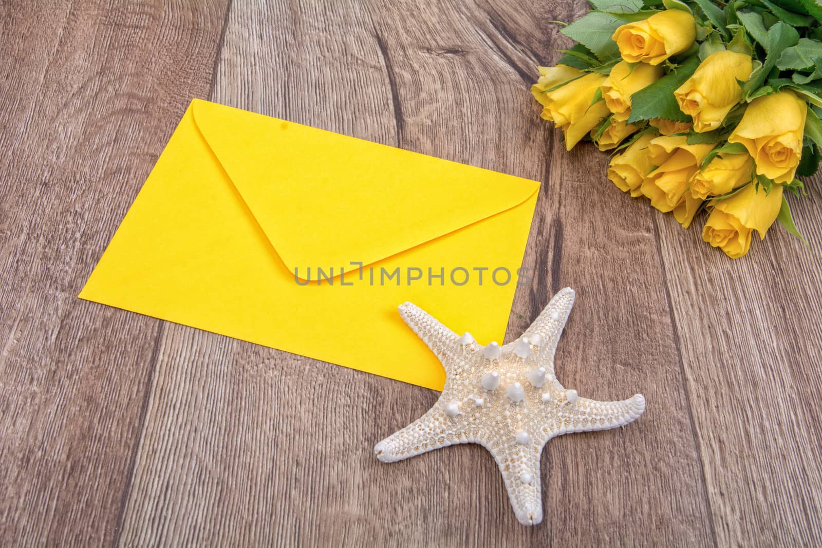 Envelope, white starfish and roses on a wooden background