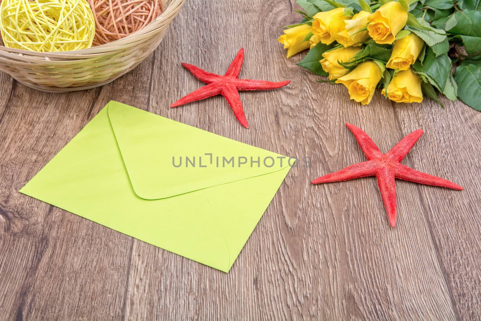 Envelope, white starfish and roses on a wooden background