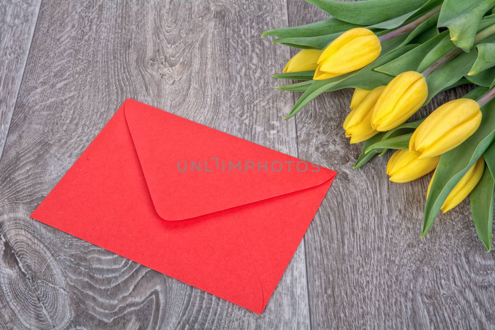 Envelope and yellow tulips on a wooden background