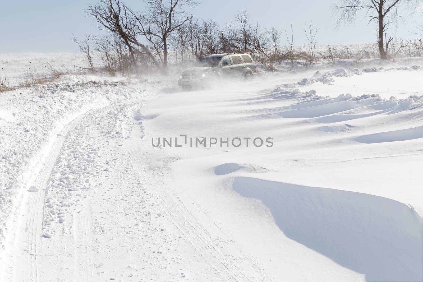A vehicle driving in blowing drifting snow on a rural road in Pennsylvania, USA.