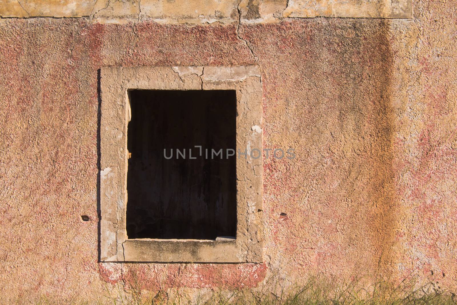Weathered facade of an abandoned house with a built frame for the window, already without a wooden frame and glass.
