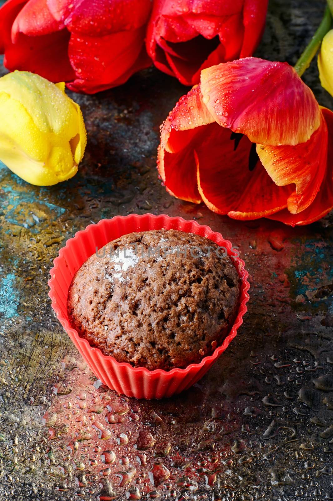 Sweet cupcake in silicone mould and a bouquet of spring tulips