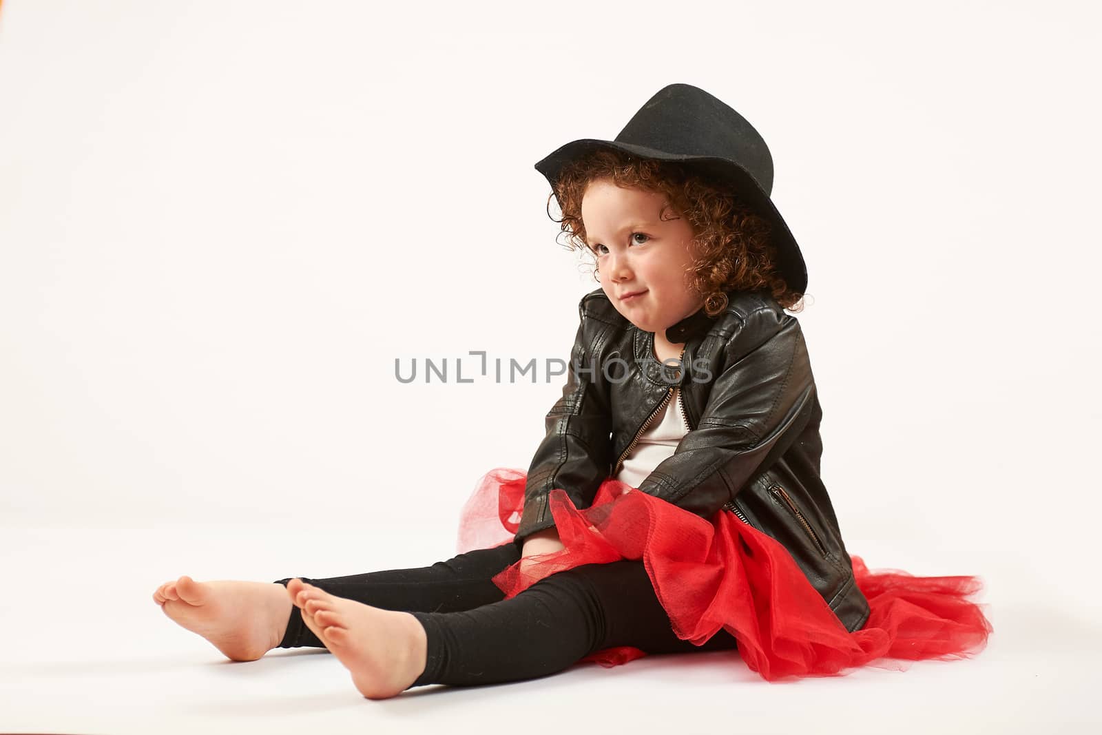 Little girl with black hat sitting and looking up