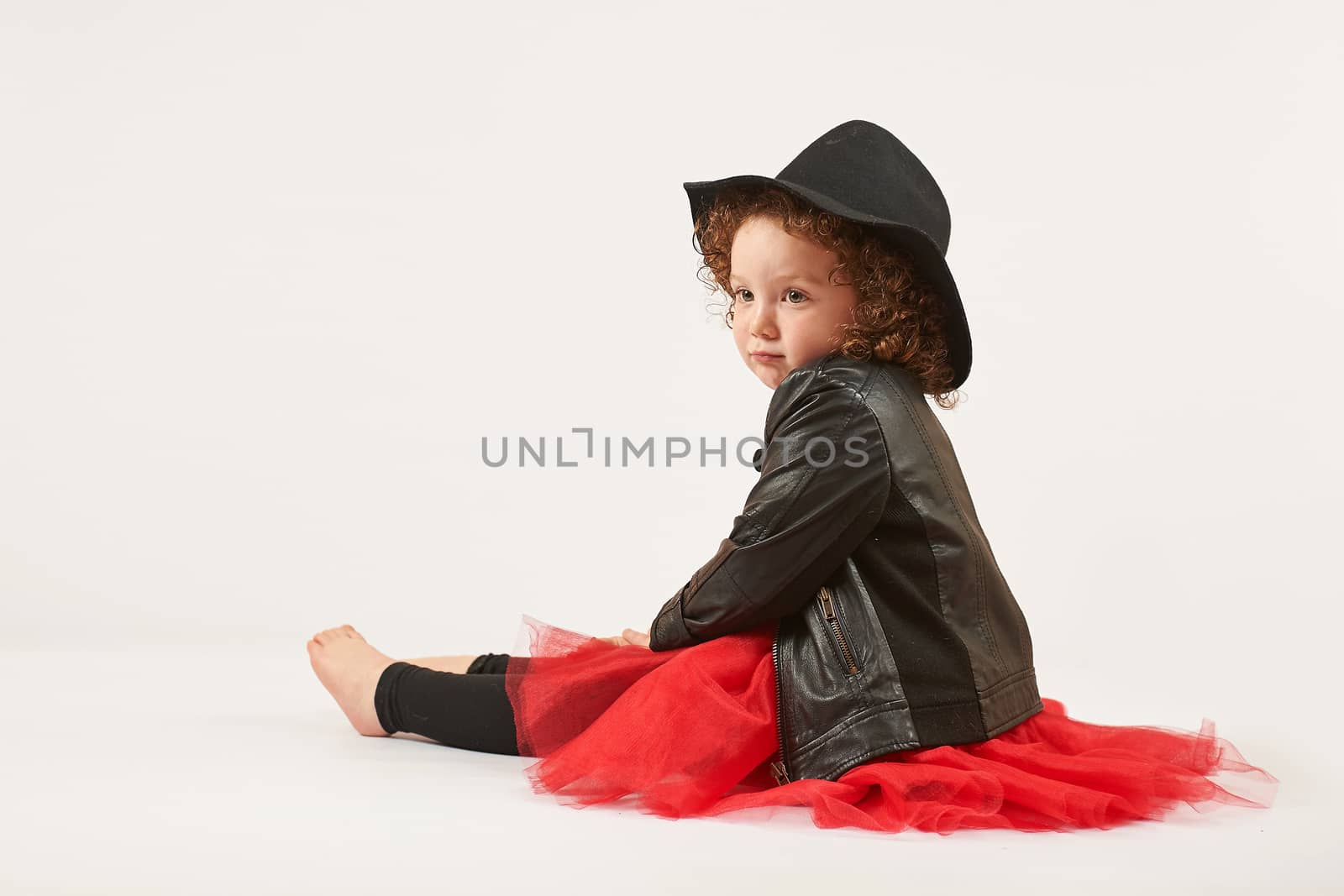 Little girl with black hat sitting and thinking