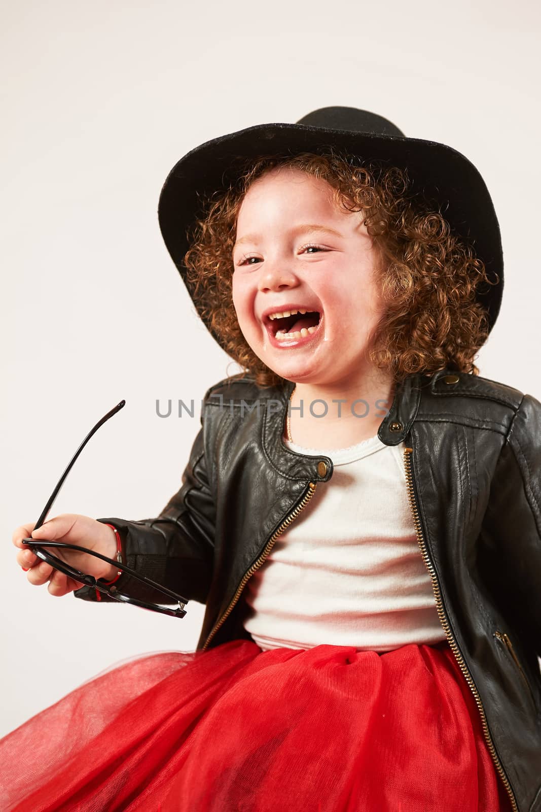 Little girl with black hat sitting and laughing