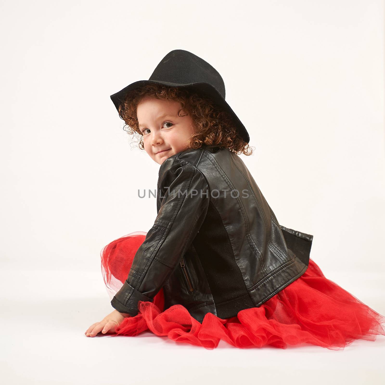 Little girl with black hat sitting and smiling