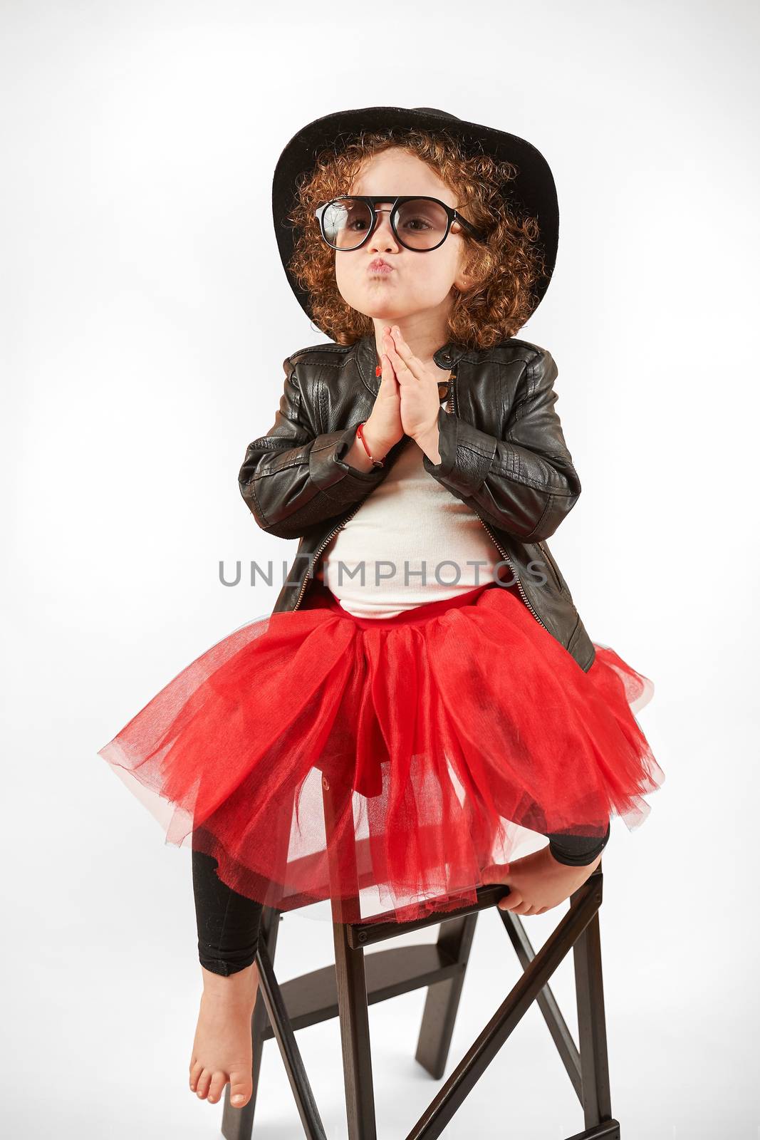 Little girl with black hat sitting on a high stool and dabbles