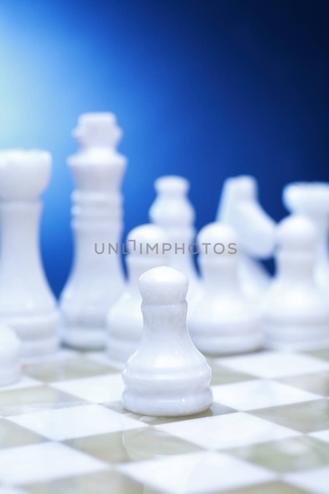 Chess pieces made from Onyx on board against blue background