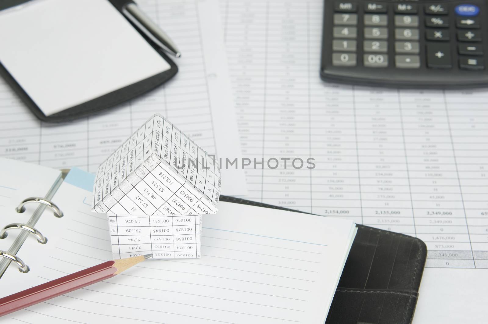 House and pencil on notebook  have blur calculator and notepad with pen on finance account as background.