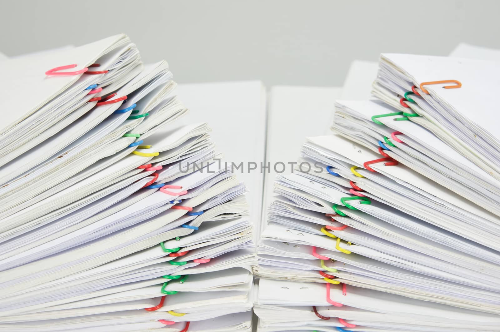 Close up step pile overload document of receipt and report with colorful paperclip on white table.