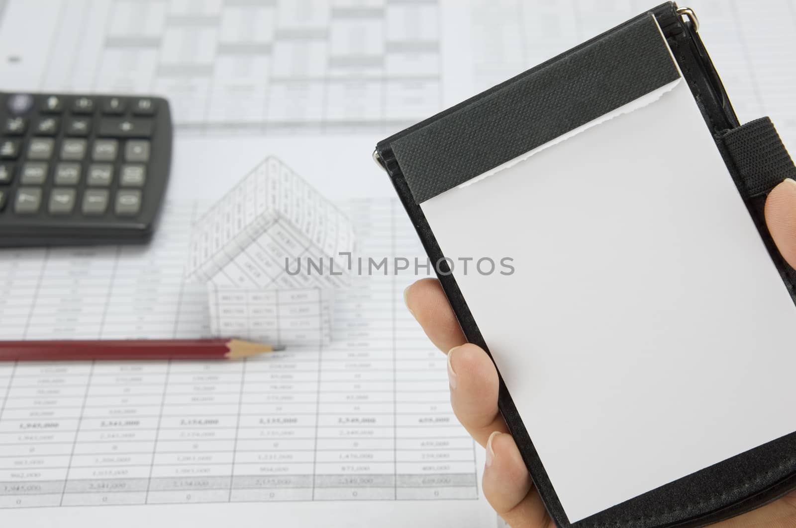 Man holding notepad have blur pencil and house as background by eaglesky