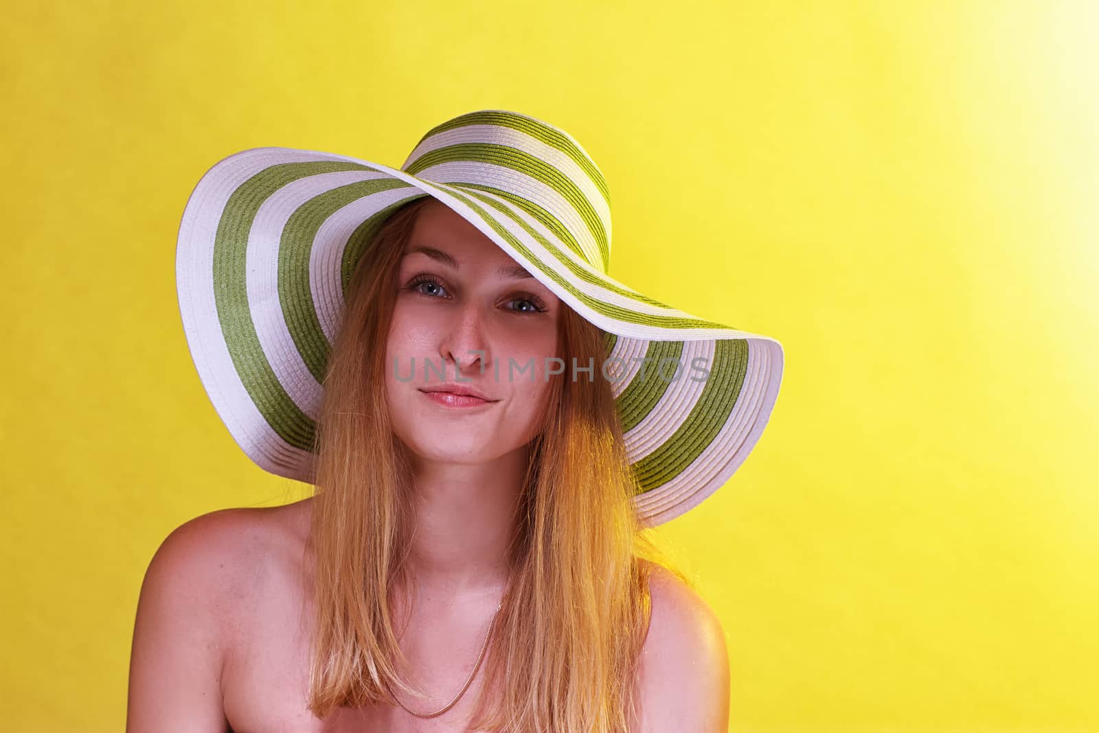 Smiling beautiful girl with beach hat and glasseson yellow background
