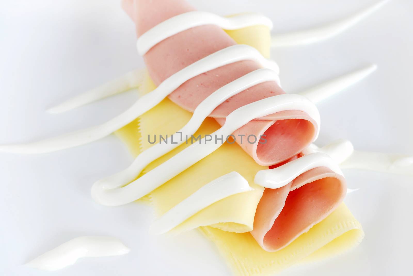 two hum and cheese slices rolled with mayonnaise over white plate