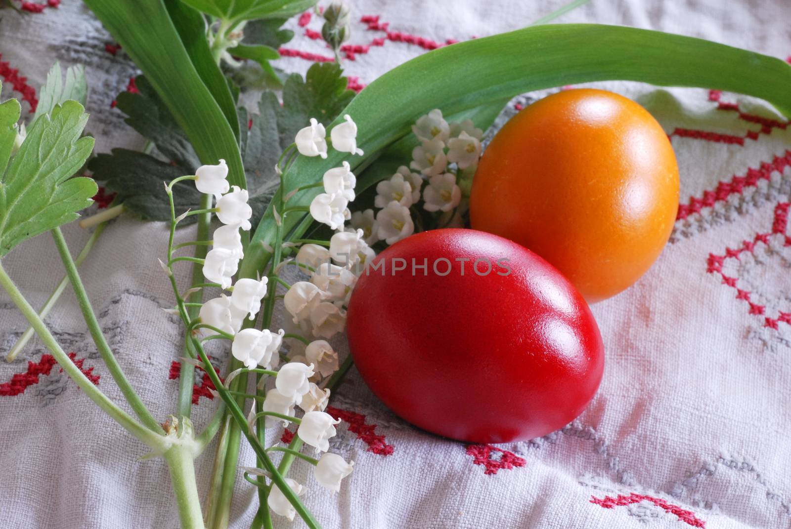 shining red and orange Easter eggs with lily of the valley plant