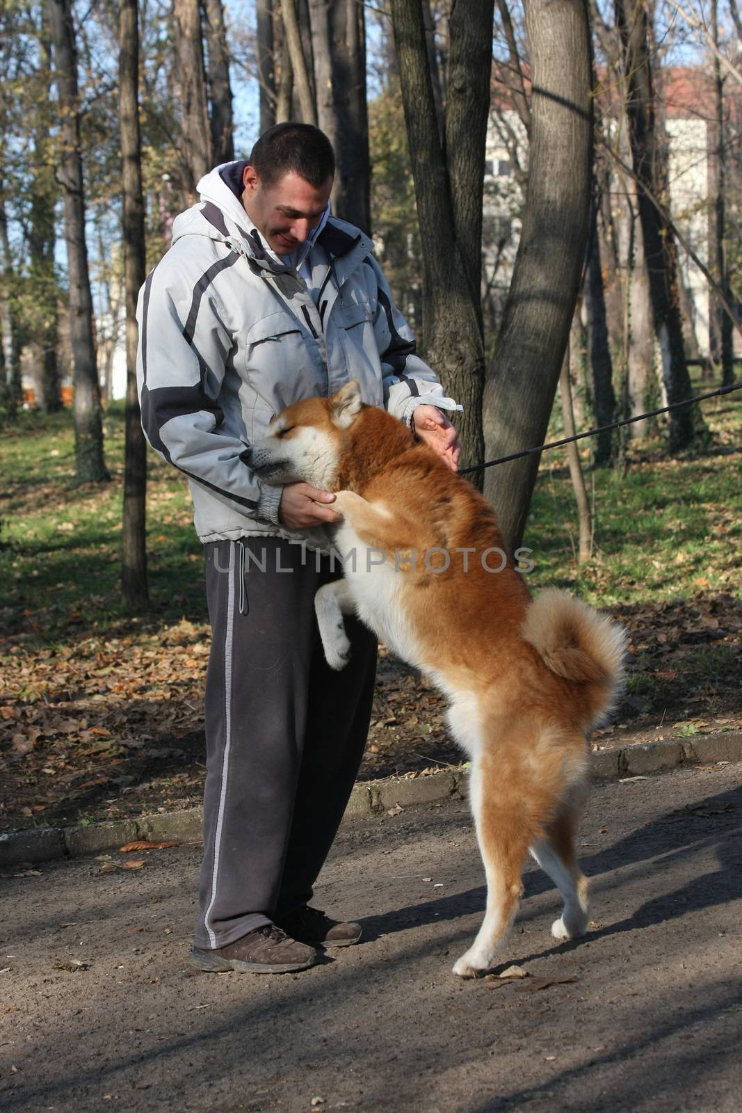 Man and joyful dog in public park by tdjoric