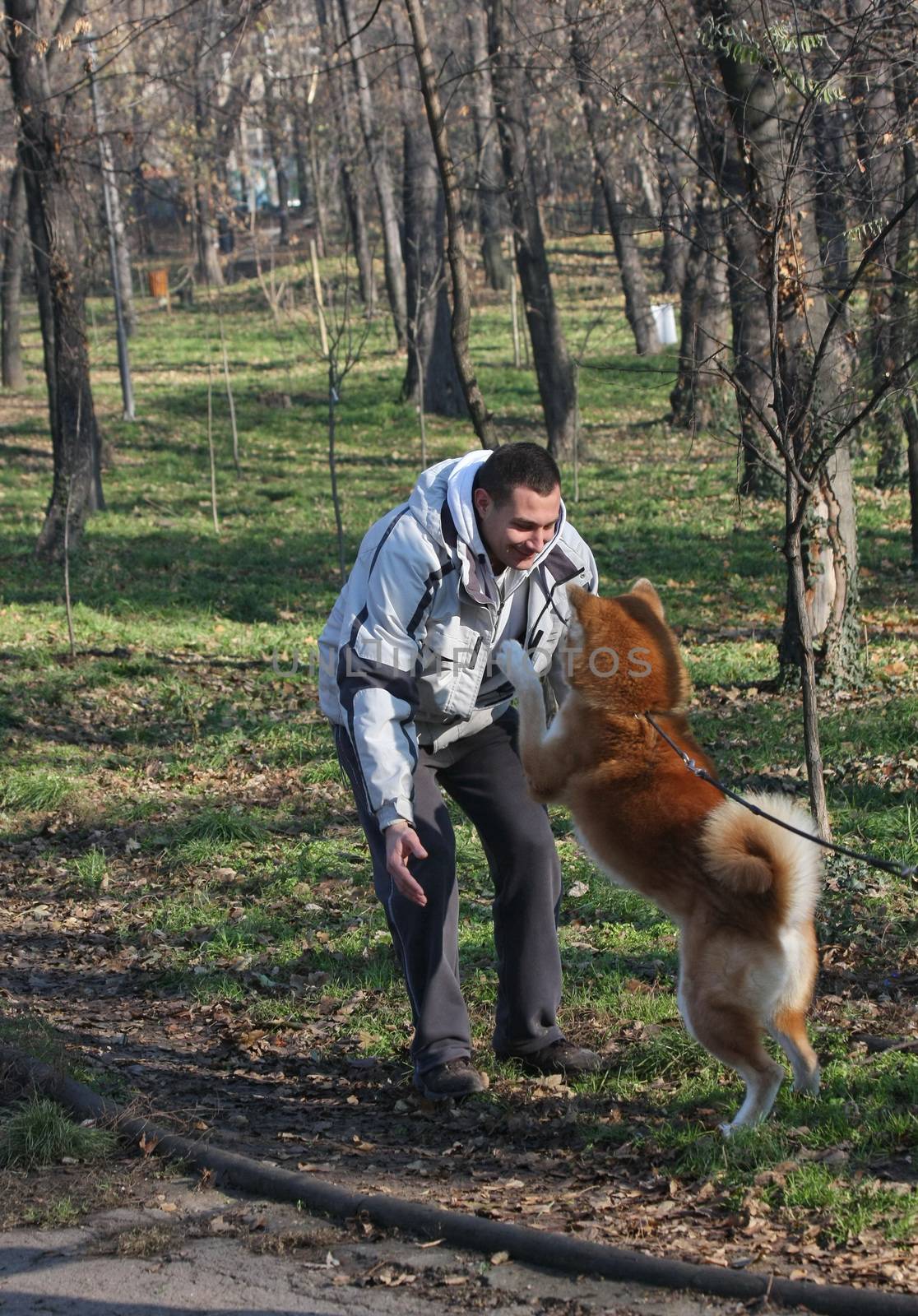 Man and joyful dog in public park by tdjoric