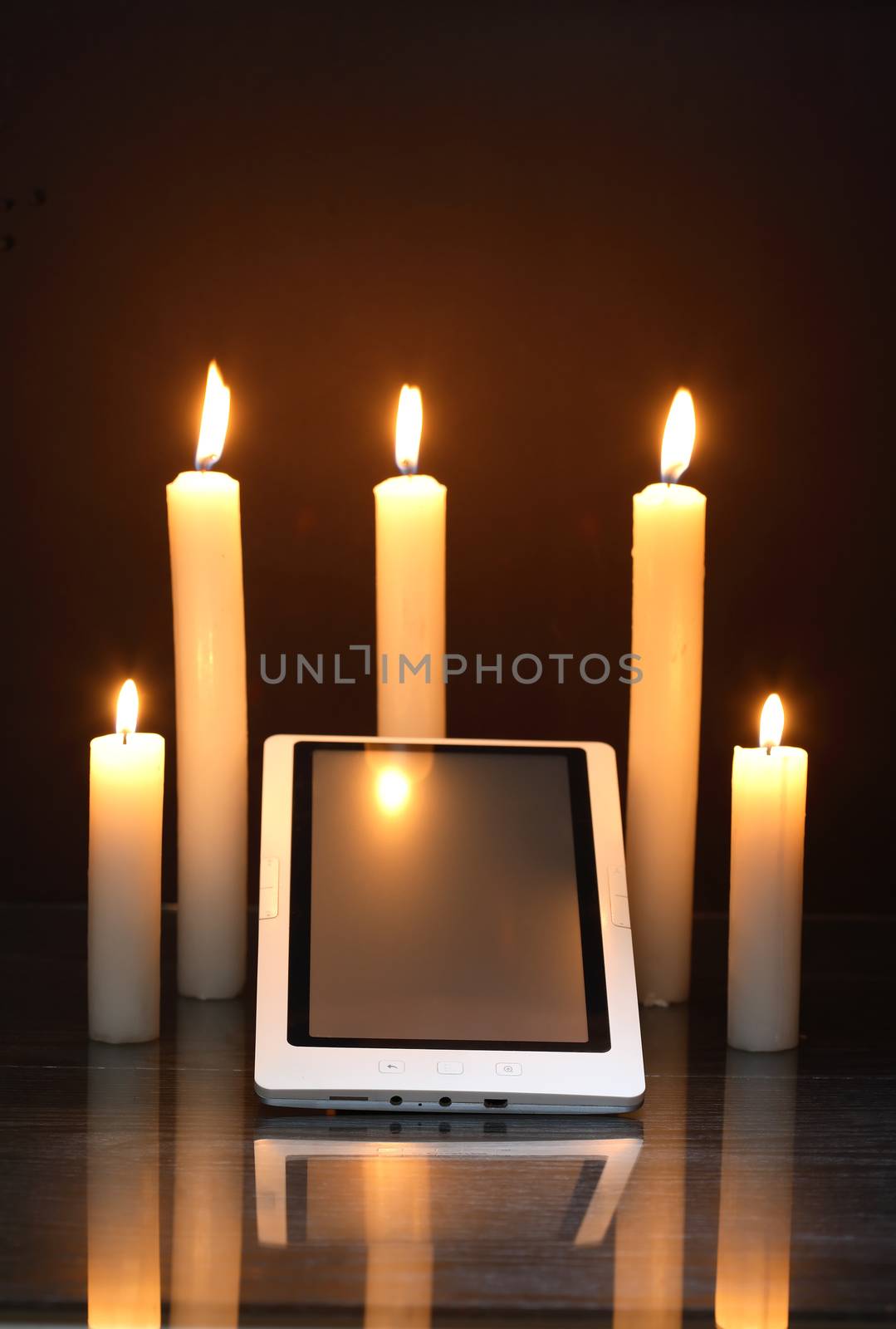 Blackout concept. Lighting candles around tablet like a sanctuary