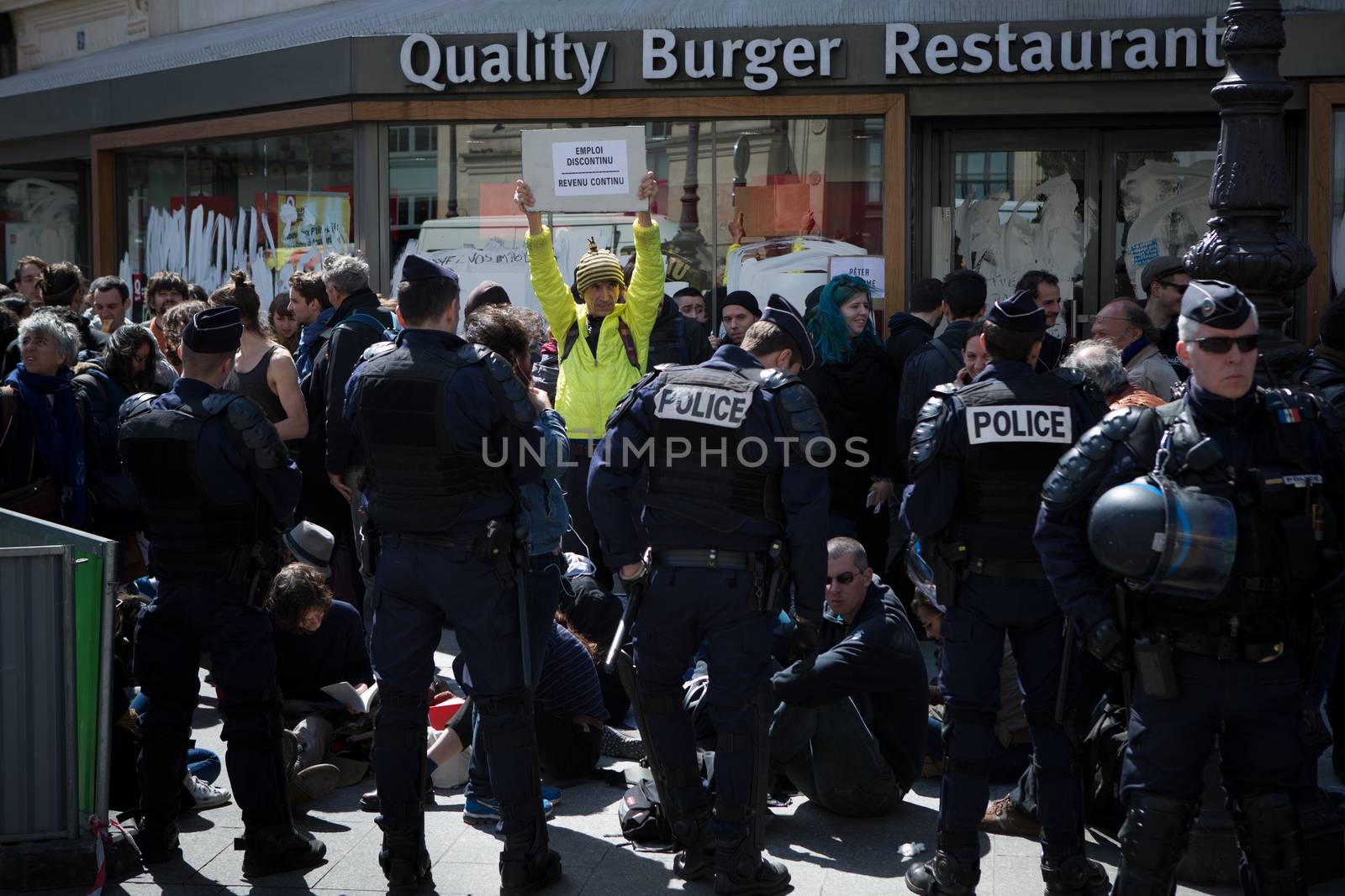 FRANCE, Paris : Demonstrators part of the Nuit Debout movement face police officers during a protest against split shifts and to demand wage increases in front of a fast food restaurant in Paris on April 20, 2016. 