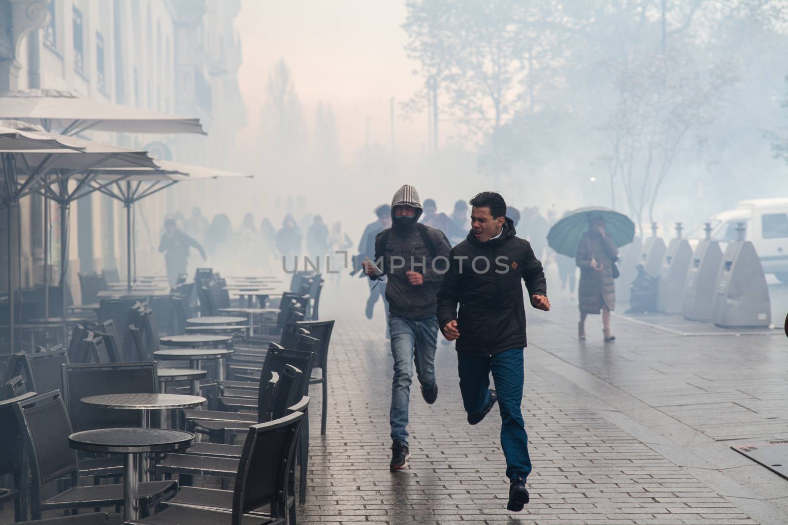 FRANCE, Nantes: Protesters run away from tear gas thrown by riot police as hundreds demonstrate against the French government's proposed labour law reforms on April 20, 2016 in Nantes, western France. High school pupils and workers protest against deeply unpopular labour reforms that have divided the Socialist government and raised hackles in a country accustomed to iron-clad job security.