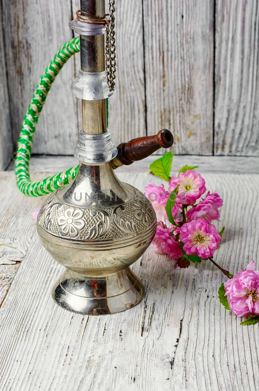 Stylish metal Arabic hookah, and small flowers of wild rose