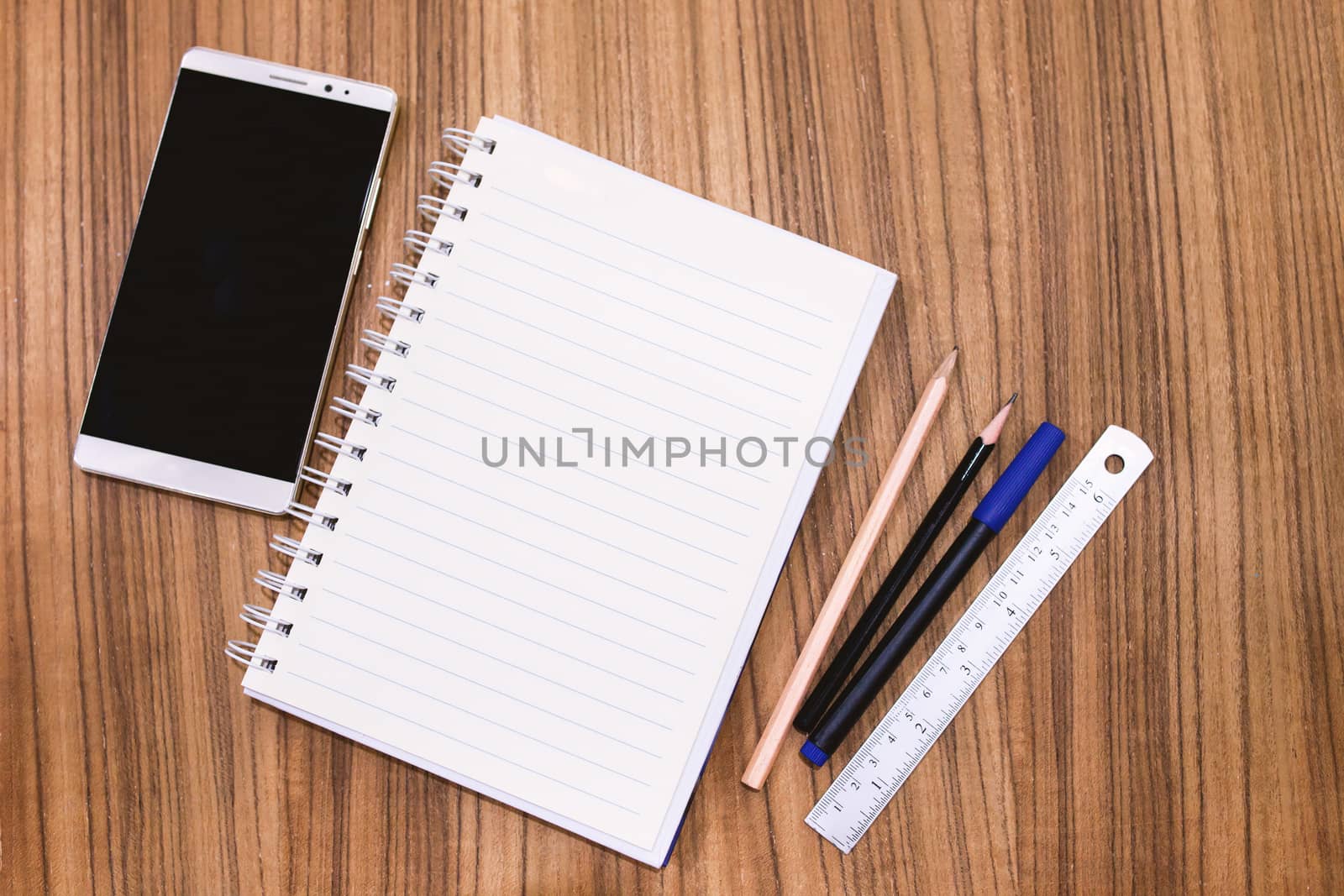 Blank note book with pencil pen and smartphone on wood table con by nopparats