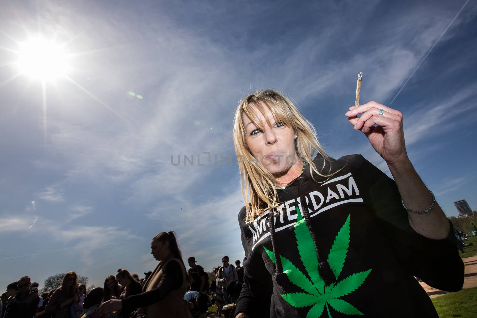 UNITED-KINGDOM, London: A woman smokes a reefer as hundreds of pro-cannabis supporters gather in Hyde Park, in London for 4/20 day, a giant annual smoke-in  on April 20, 2016. 