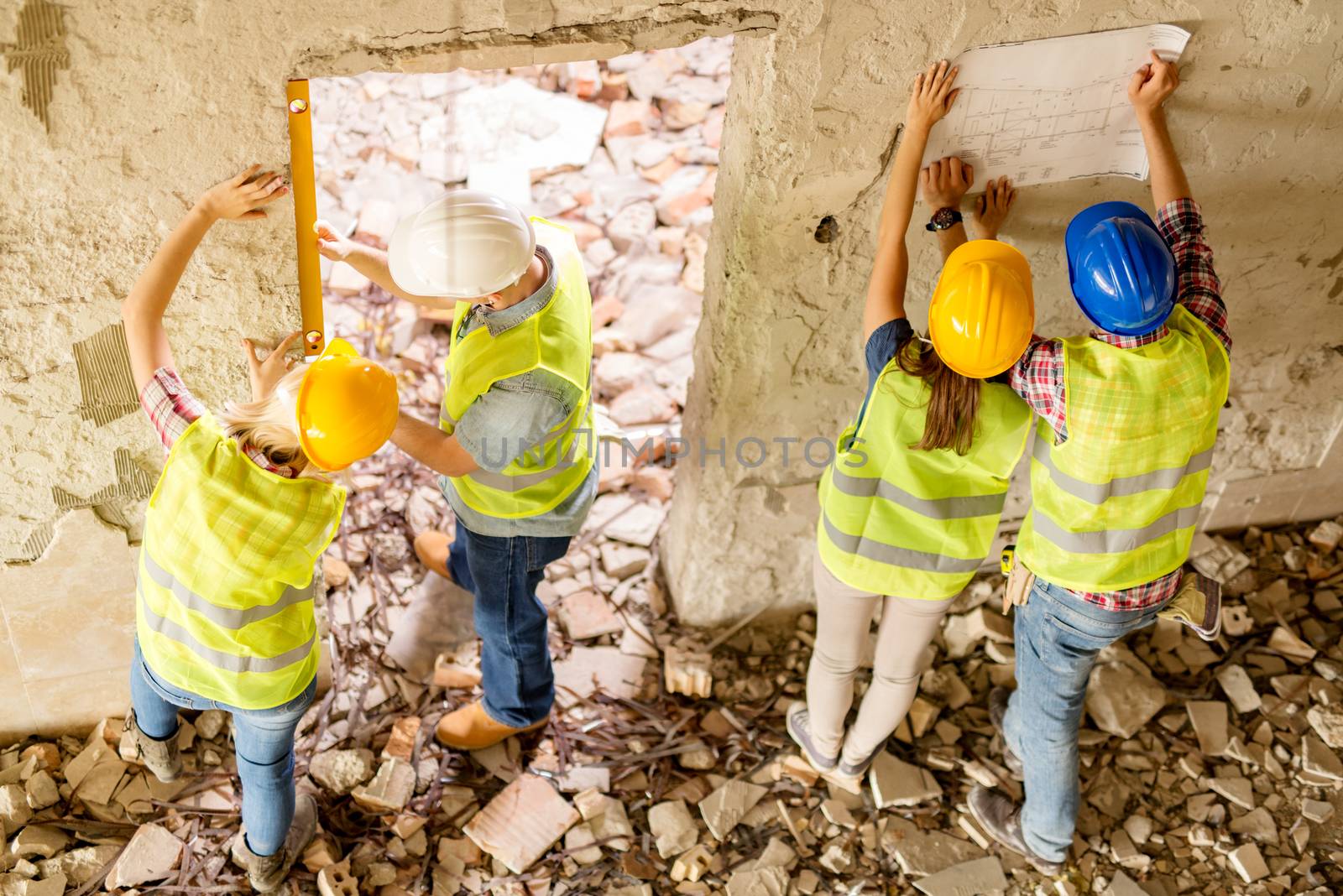 Four construction architects review plan in building damaged in the disaster.