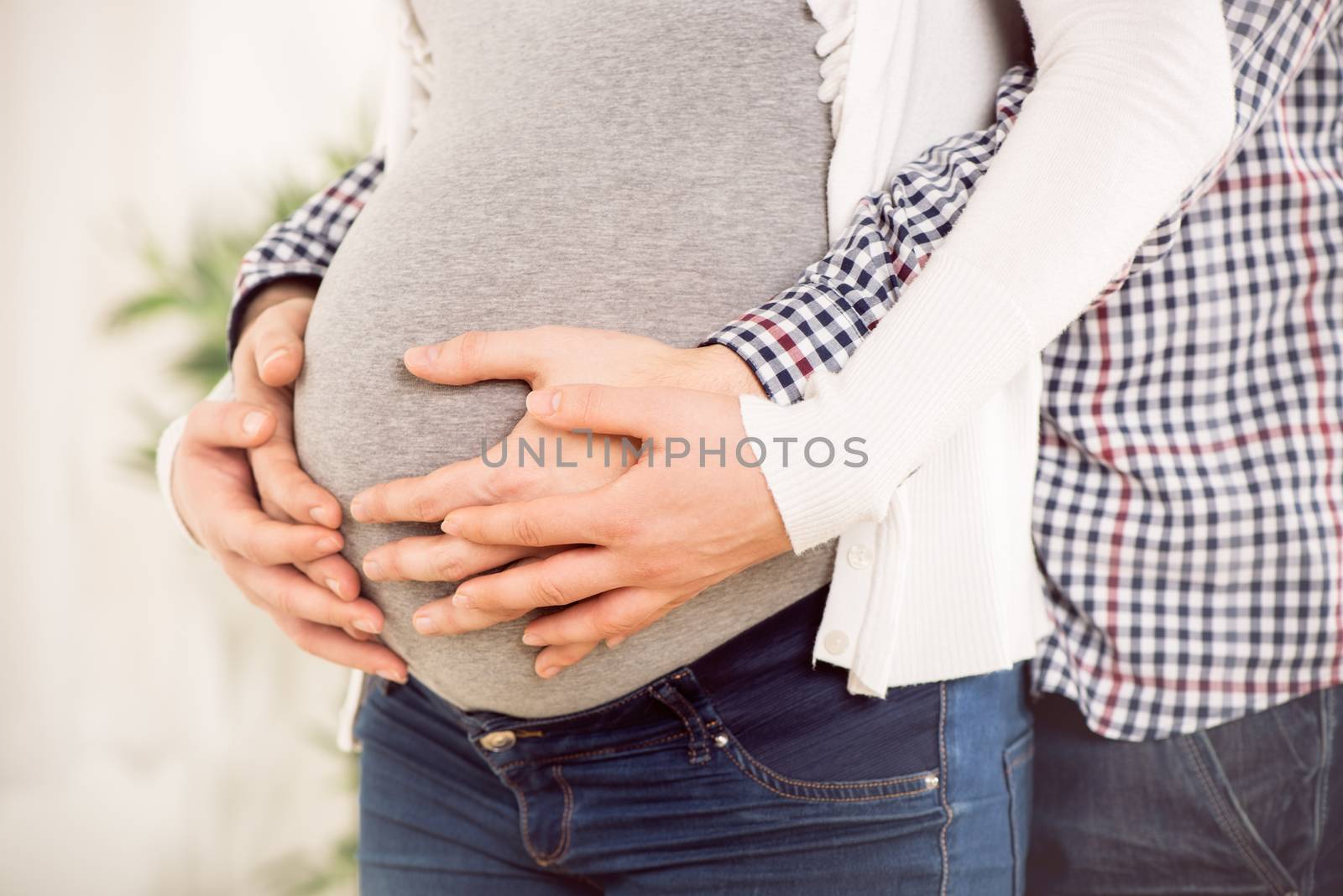 Close-up of a male and female hands holding on pregnant woman's belly. 