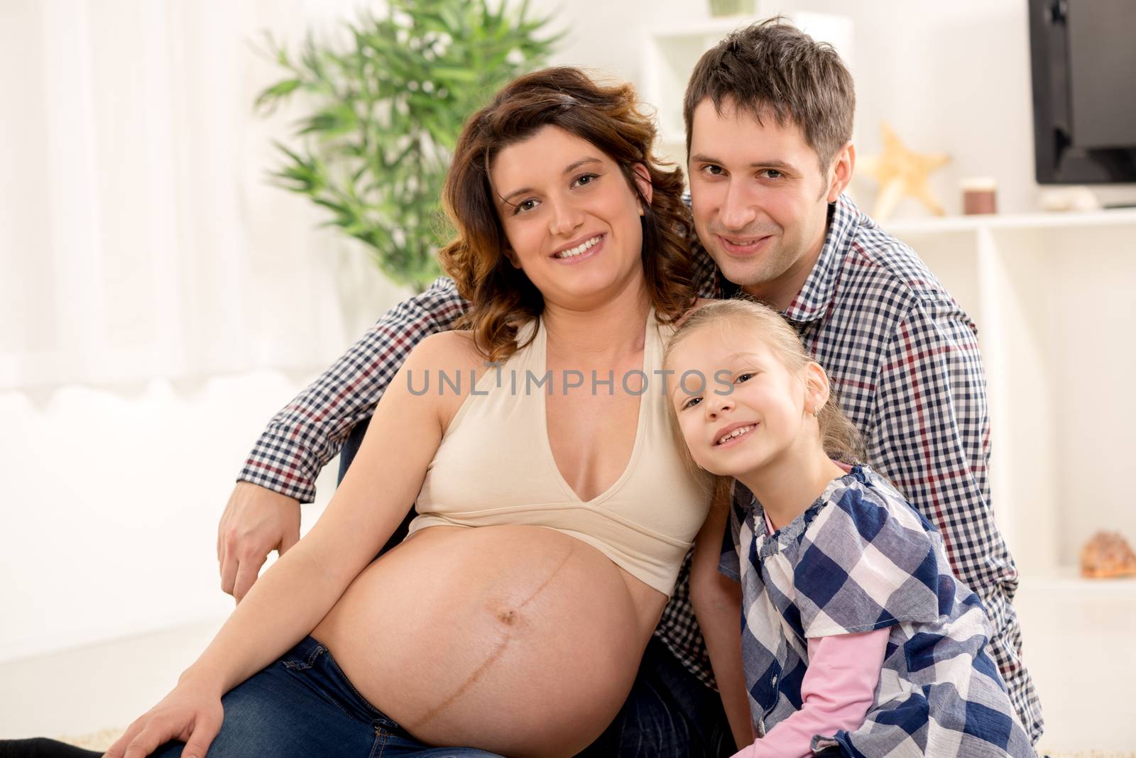 Portrait of a beautiful young family expecting a new baby. They smiling and looking at camera.