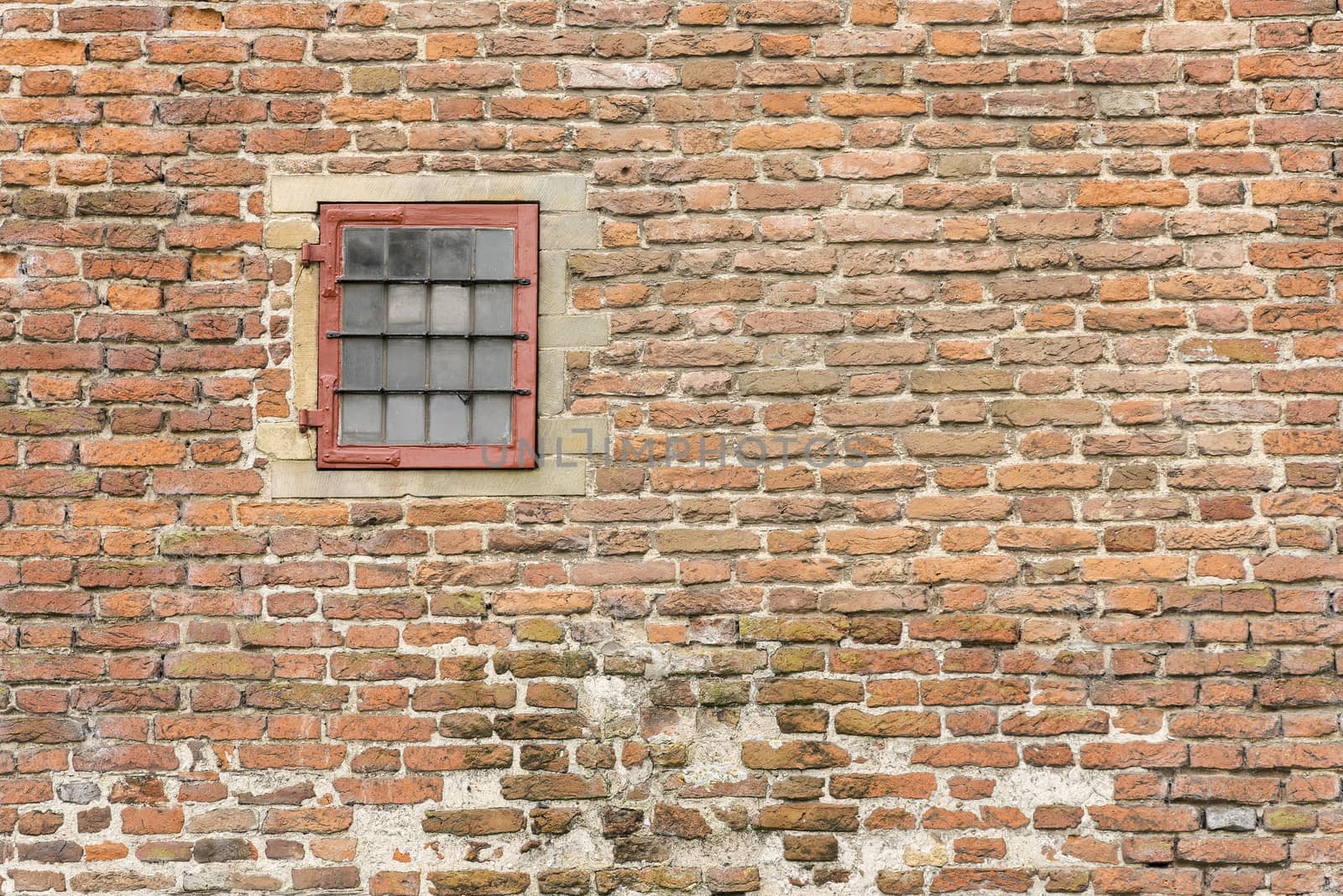 Old fortress wall with a frame and a turn window with glass rods
