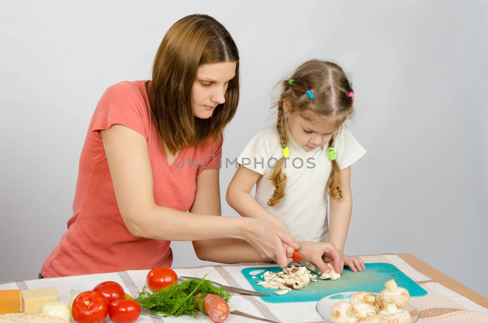 Mom shows daughter how to cut a small knife mushrooms