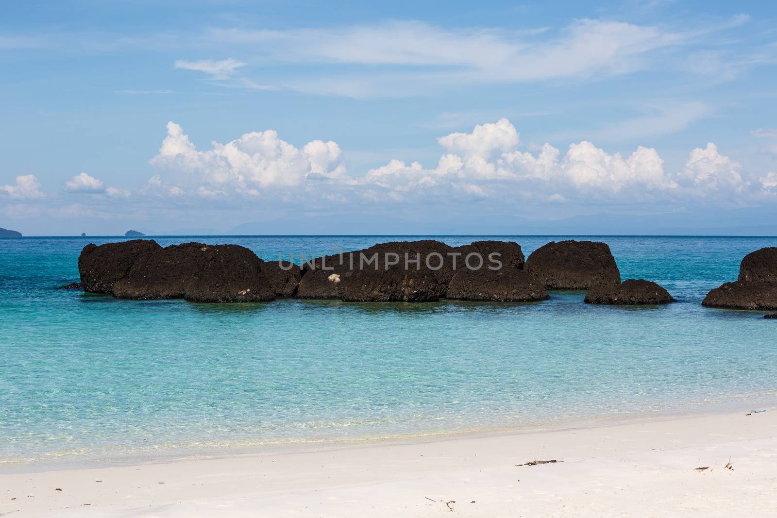 white sand blue sea and stone on beautiful beach