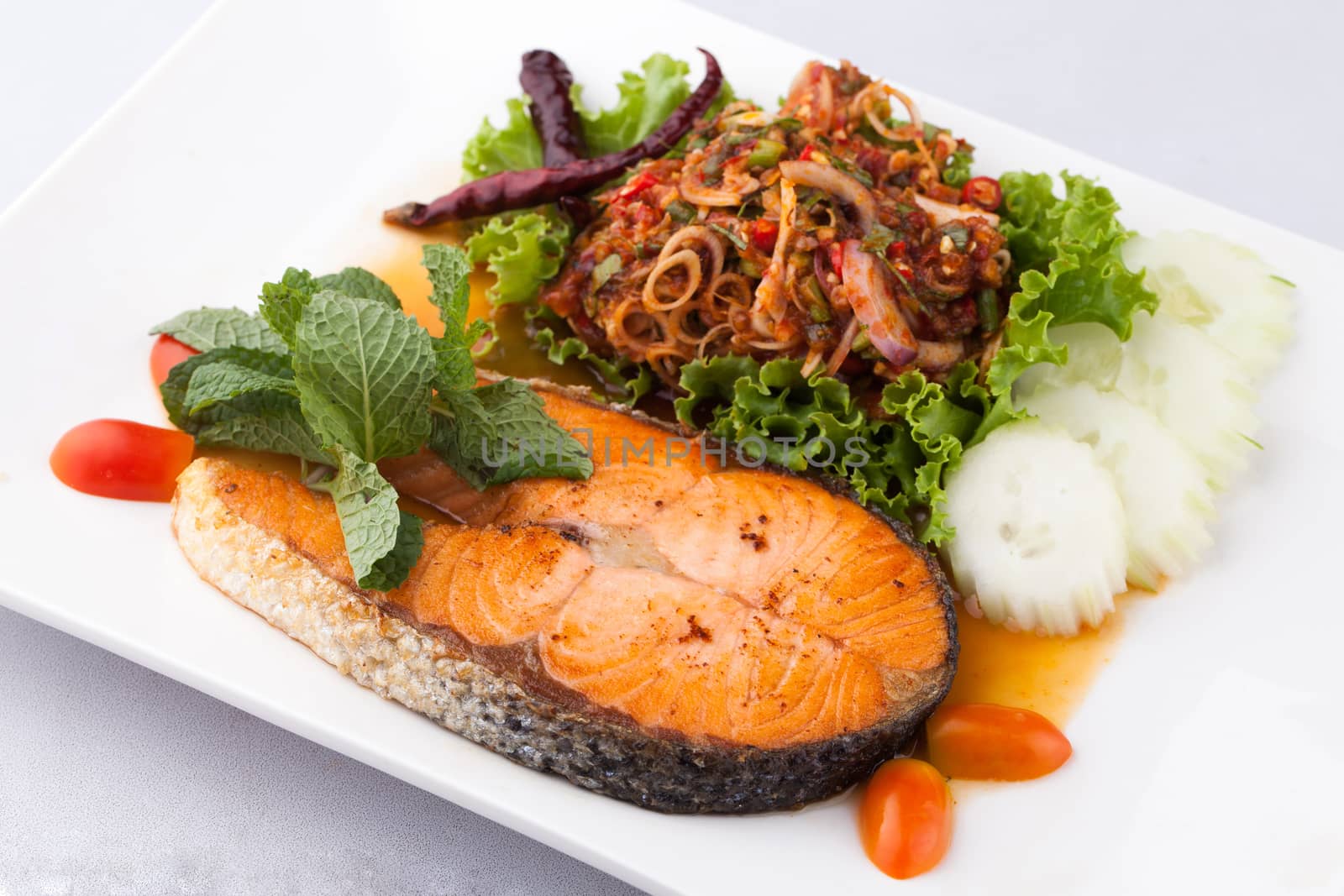 fried salmon fish with spicy salad on whith plate