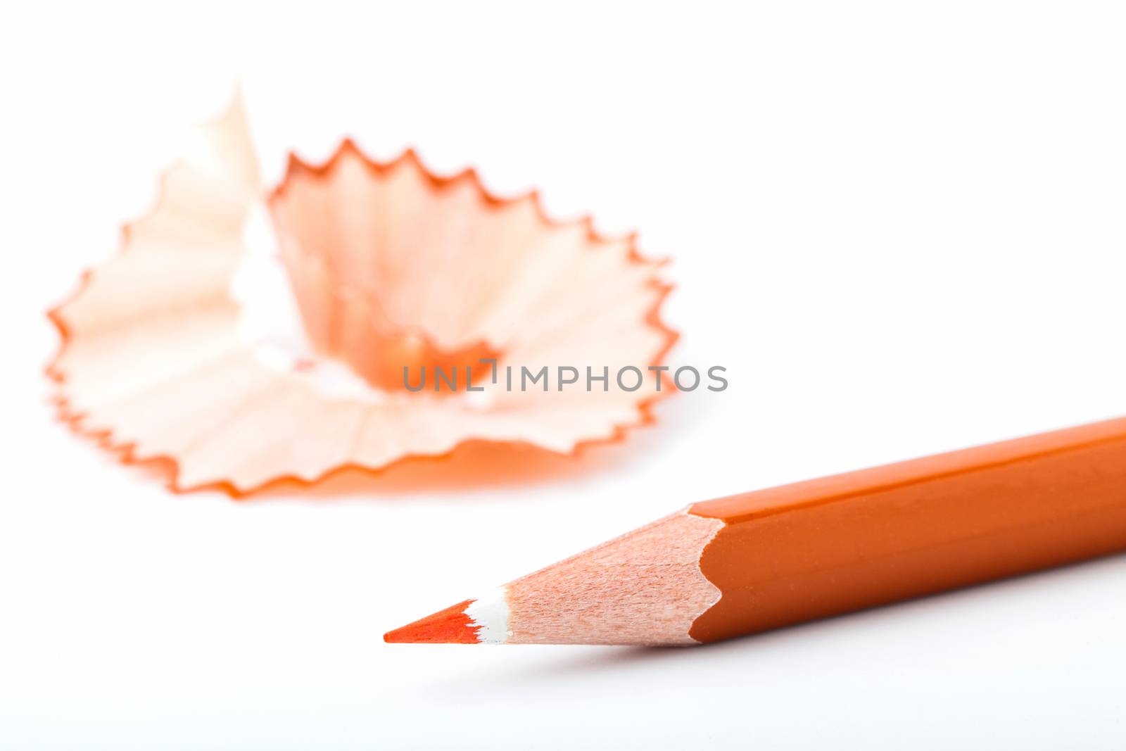 tip point of orange pencils and shavings from sharpening on white background