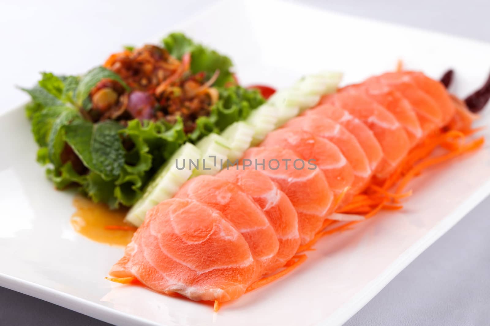 sashim salmon with spicy salad on a white plate