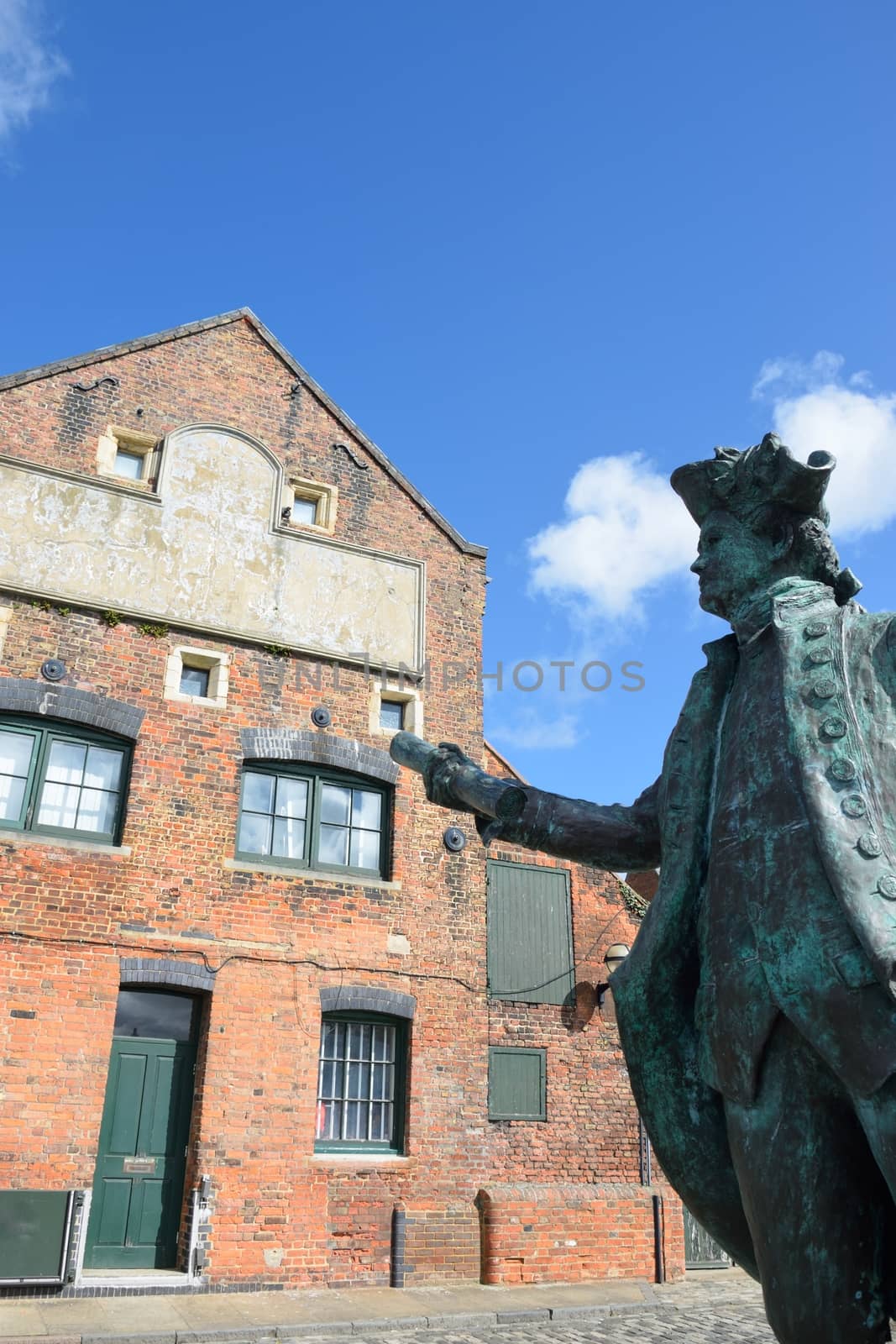 Statue of George Vancover Kings Lynn Norfolk with warehouse by pauws99